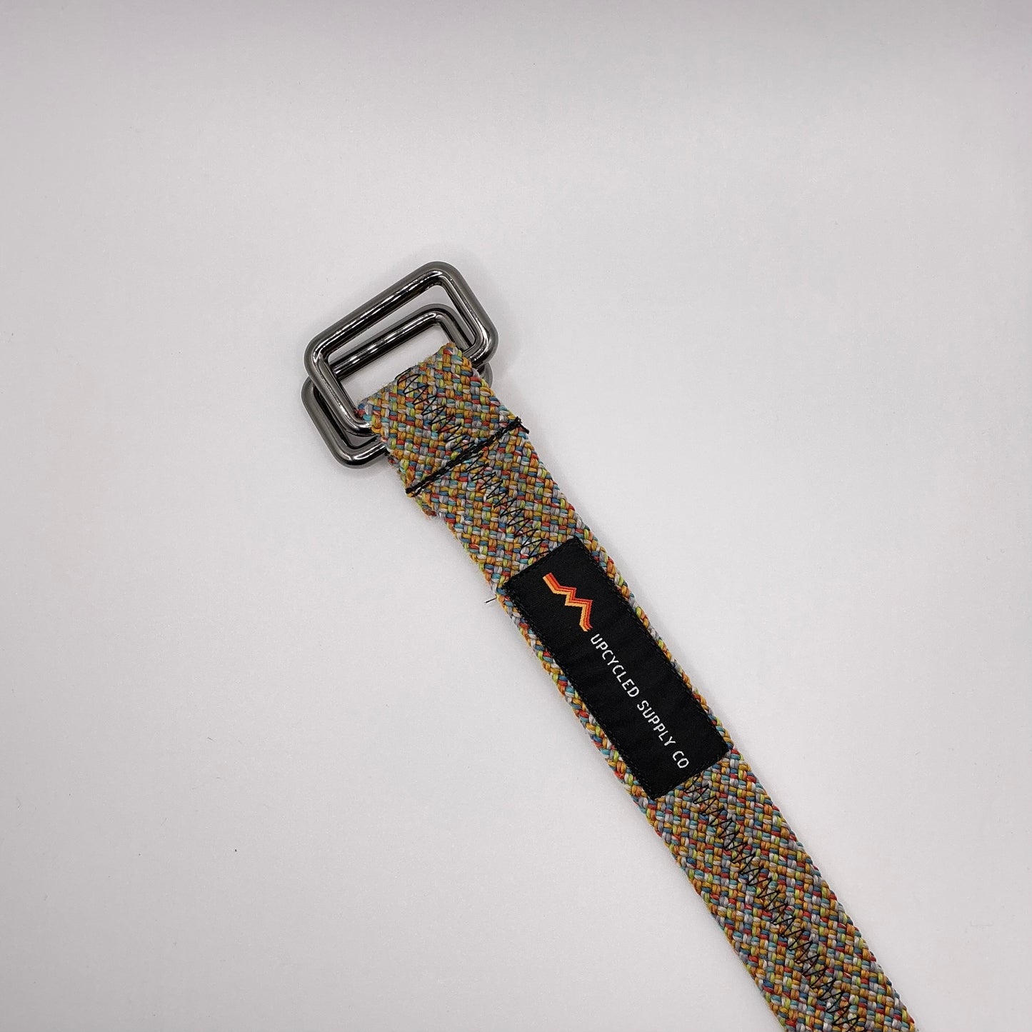 Herringbone patterned belt with a black buckle on a light gray background