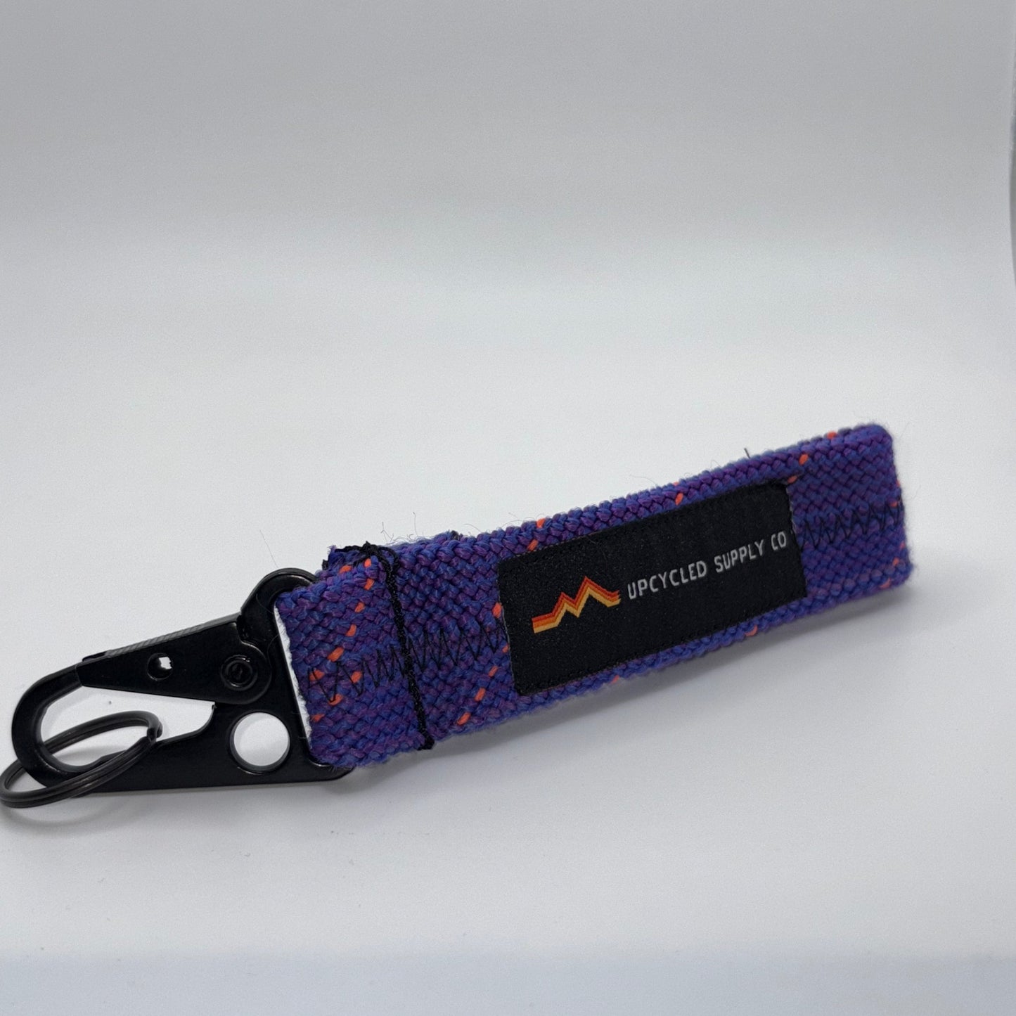 Purple dog leash with a black clip on a white background