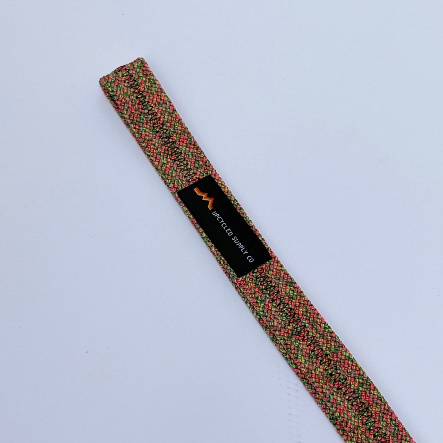 Multicolored textured belt with a brand label on a light gray background
