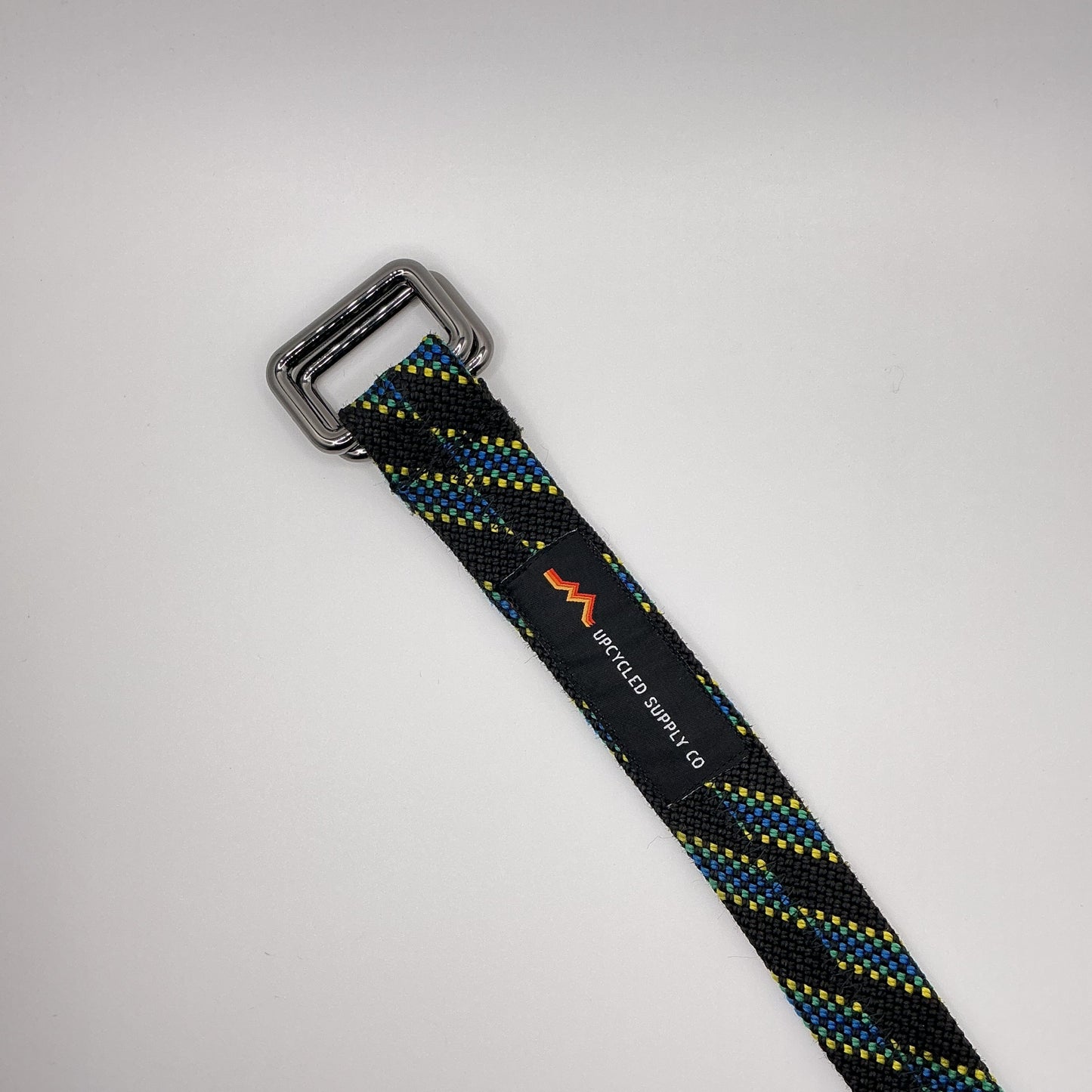 Black and blue striped strap with a metal buckle on a light gray background
