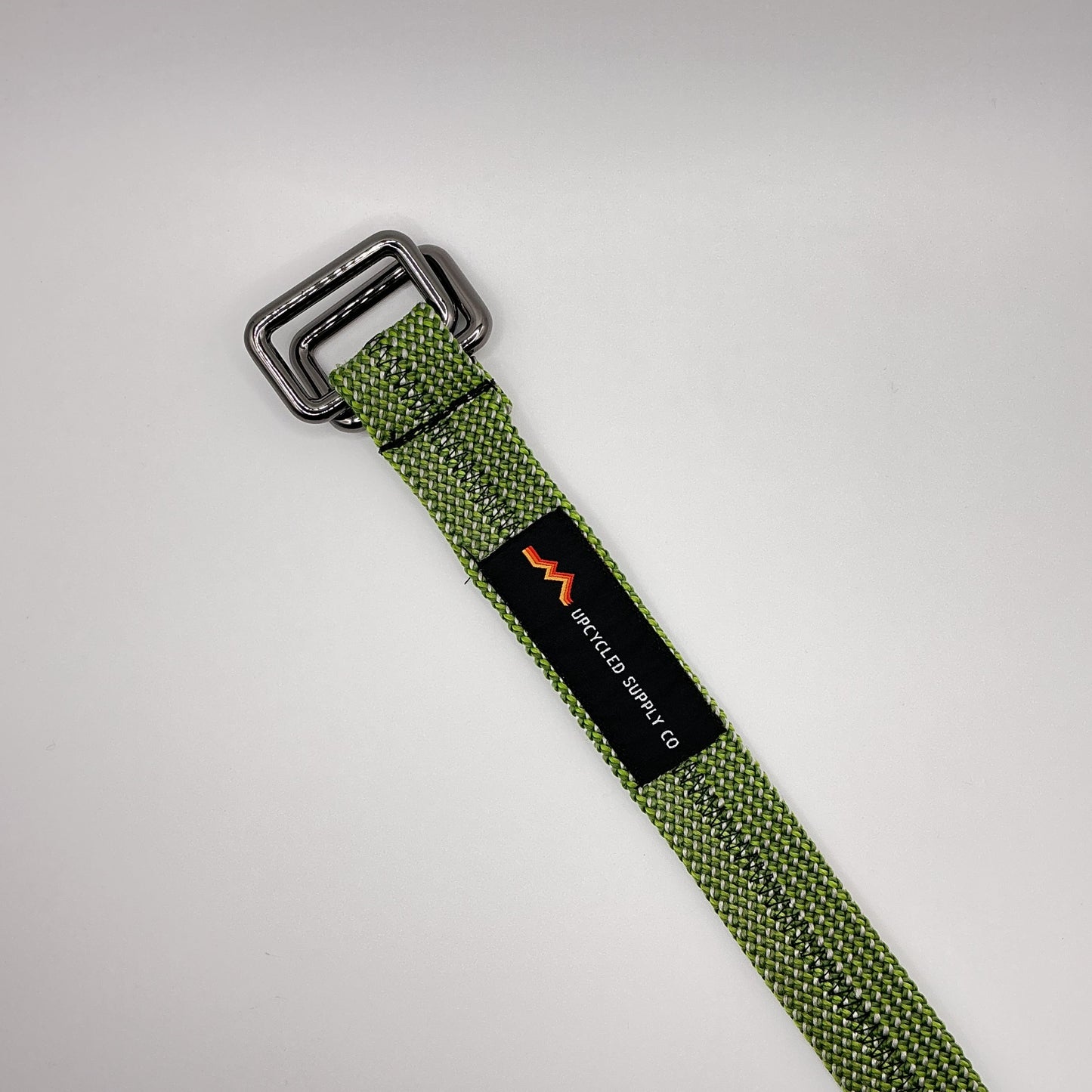 Green webbing strap with a buckle and visible brand logo on a light gray background