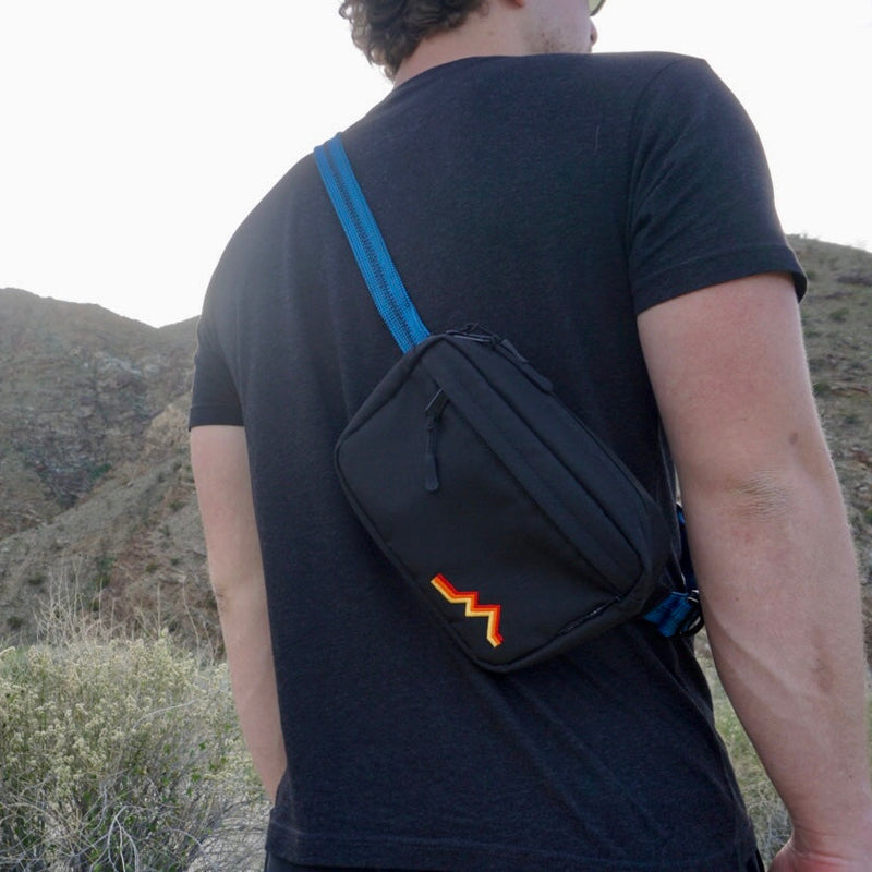 Person wearing a black bag with a logo in a desert landscape