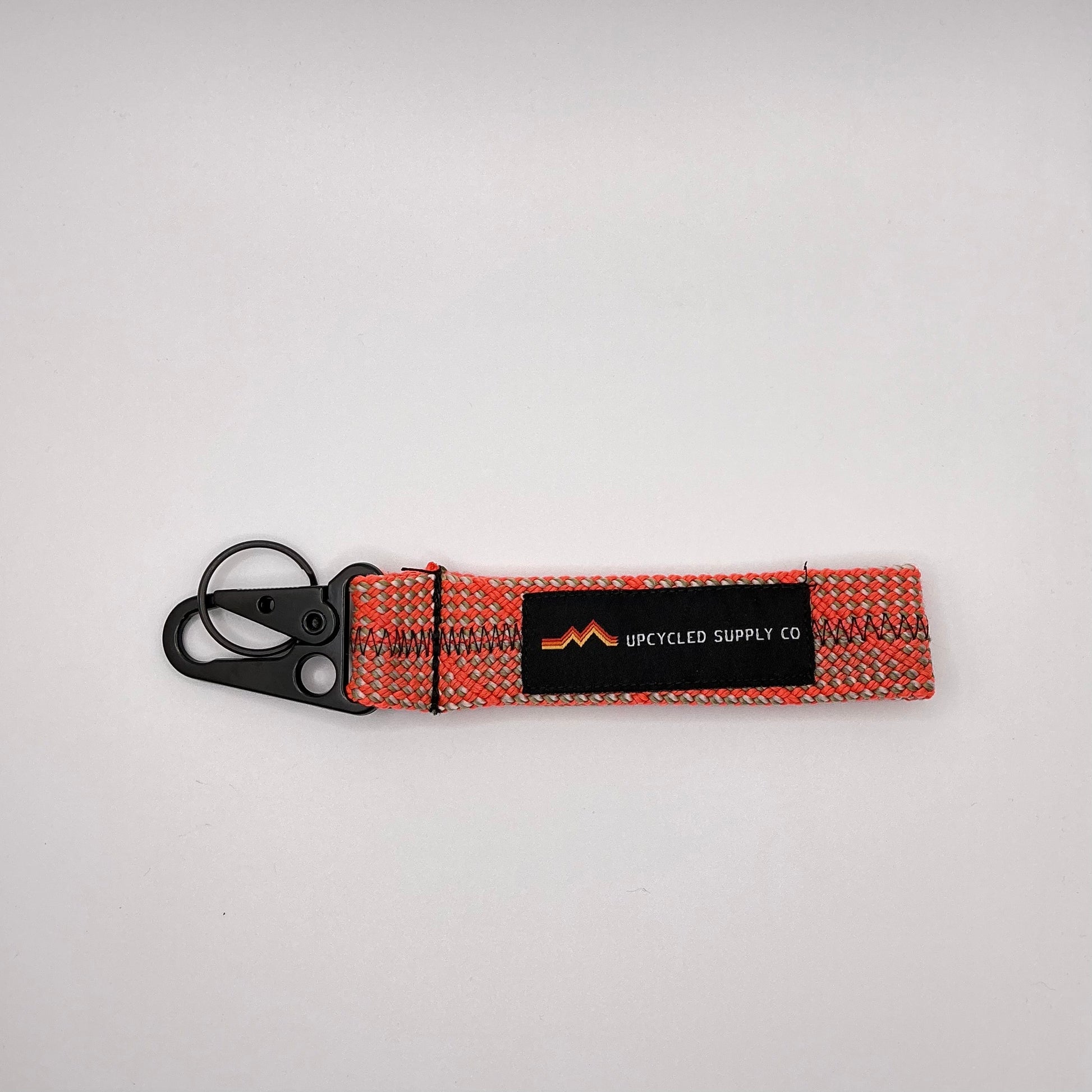 Keychain with woven design and visible brand logo on a light gray background