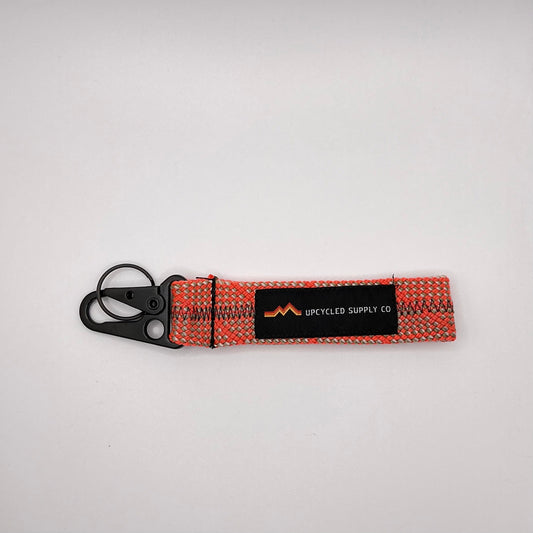 Keychain with woven design and visible brand logo on a light gray background