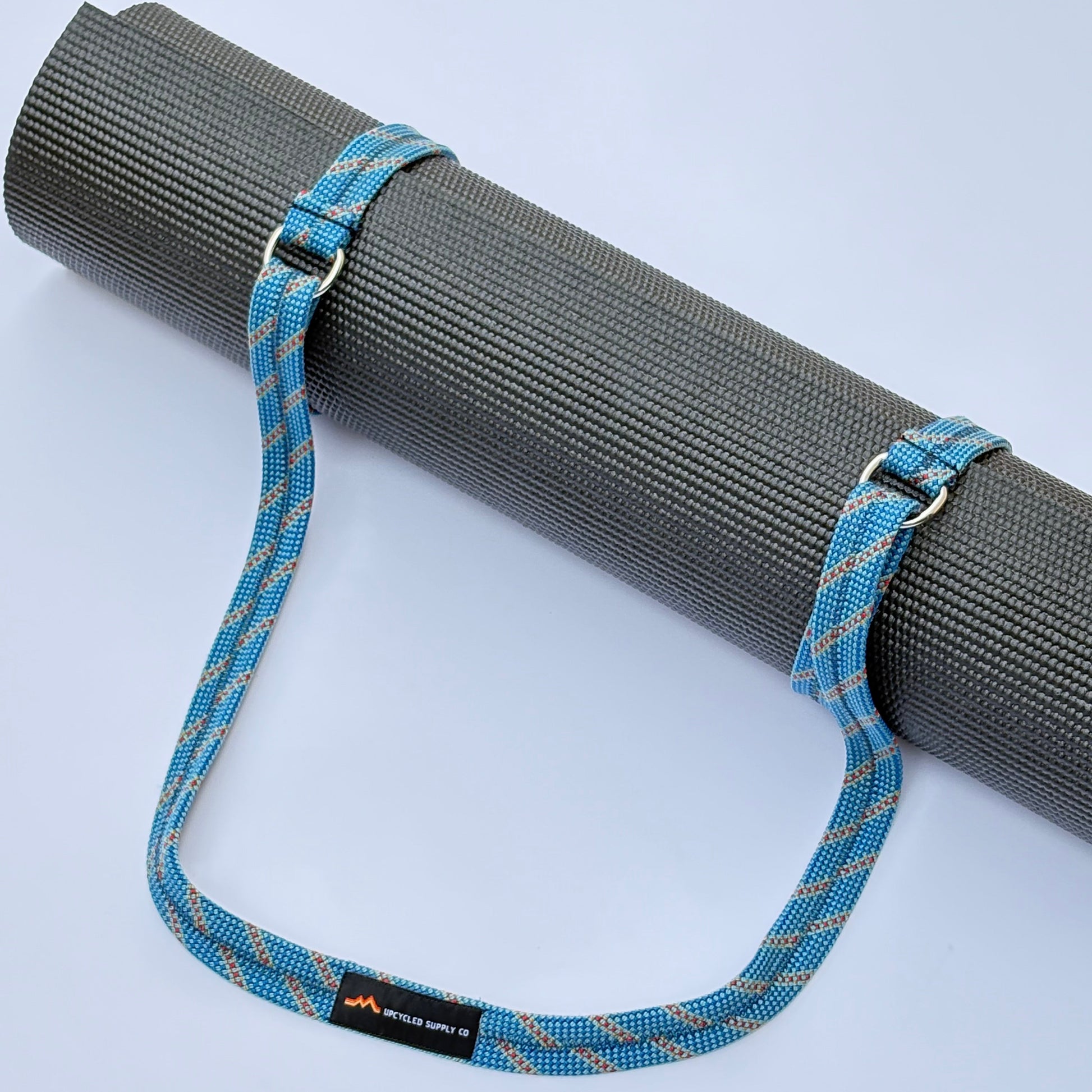 Yoga mat with a blue strap on a light gray background