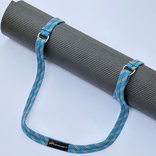 Yoga mat with a blue strap on a light gray background
