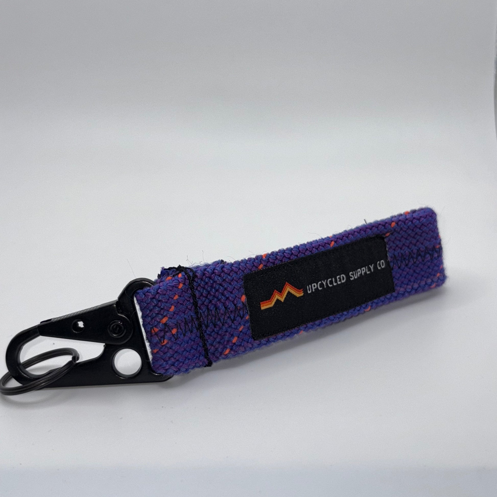 Purple dog leash with a black clip on a white background