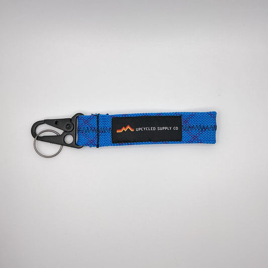 Blue keychain with a brand logo on a gray background