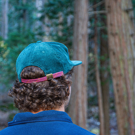 Person wearing a teal cap and blue shirt in a forest setting