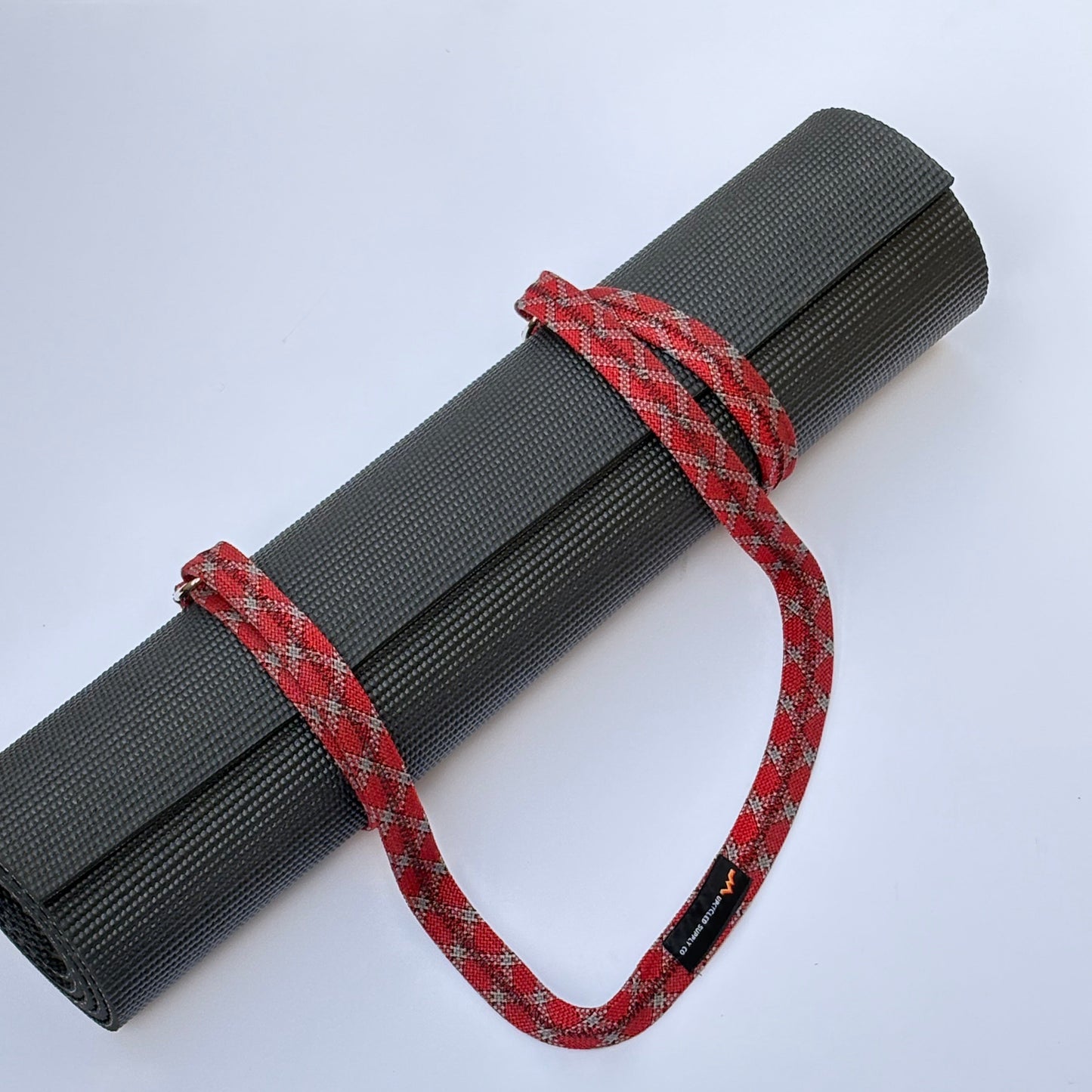 Gray yoga mat with a red and black rope on a white background