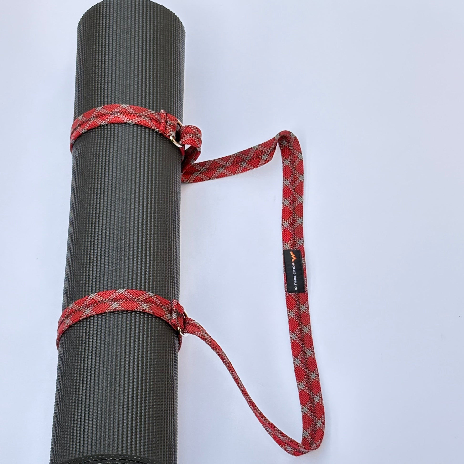 Gray yoga mat with a red strap on a white background