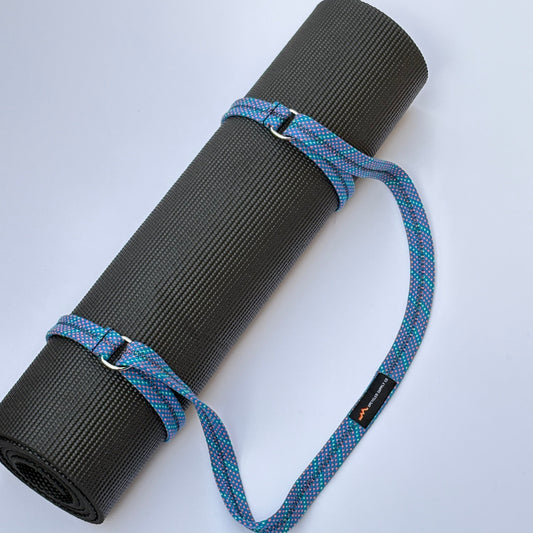 Black yoga mat with a blue strap on a white background
