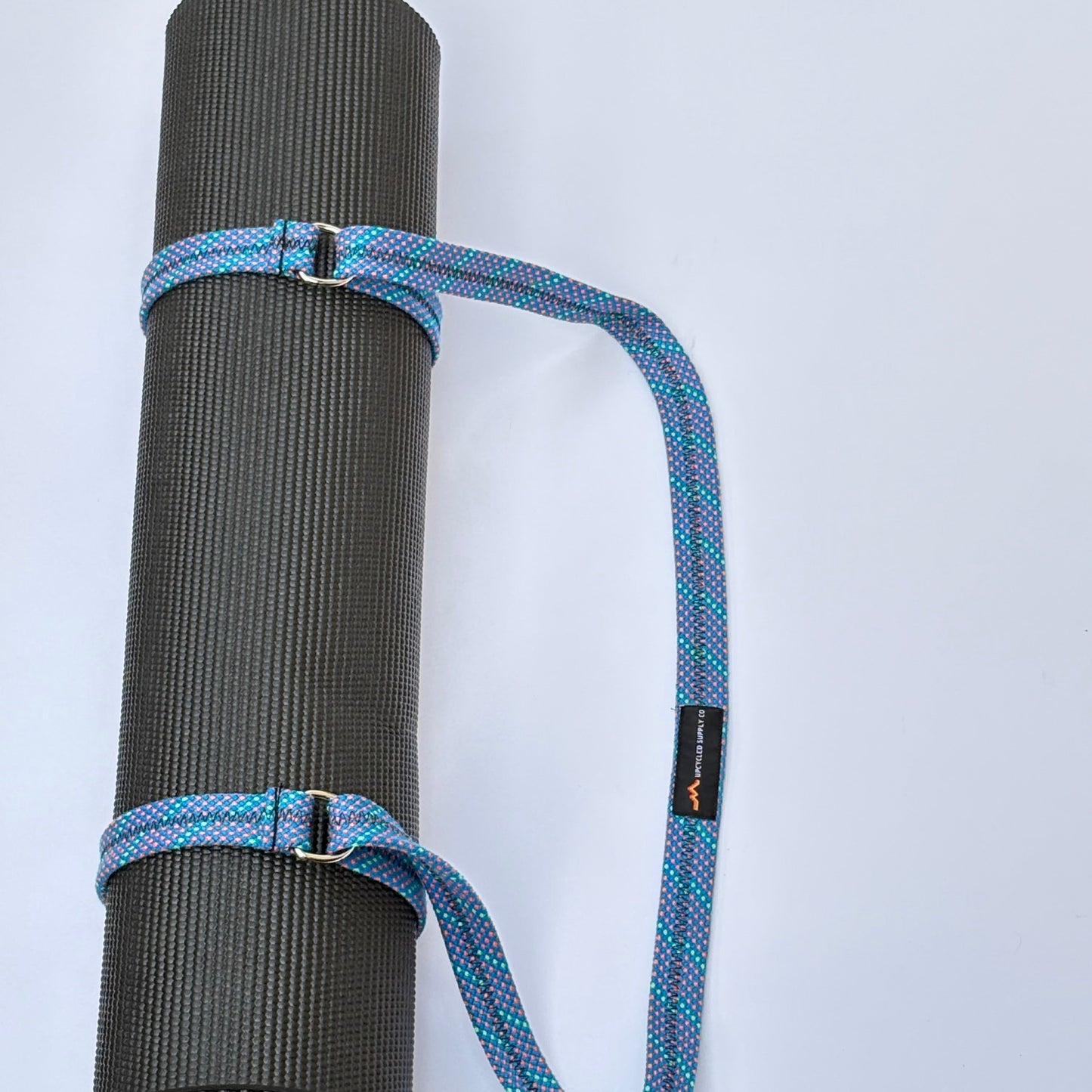 Black yoga mat with a blue carrying strap on a white background