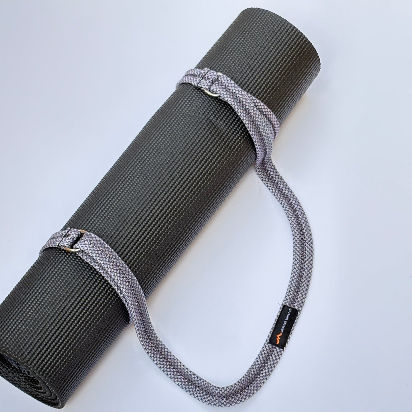 Gray yoga mat with a strap on a white background