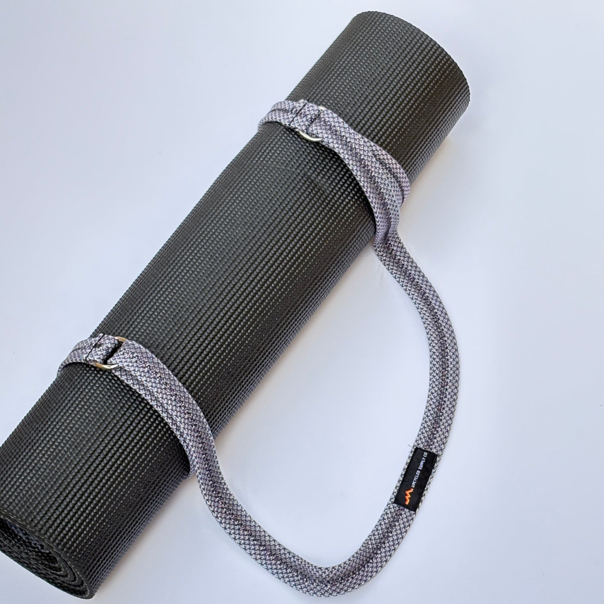 Gray yoga mat with a strap on a white background