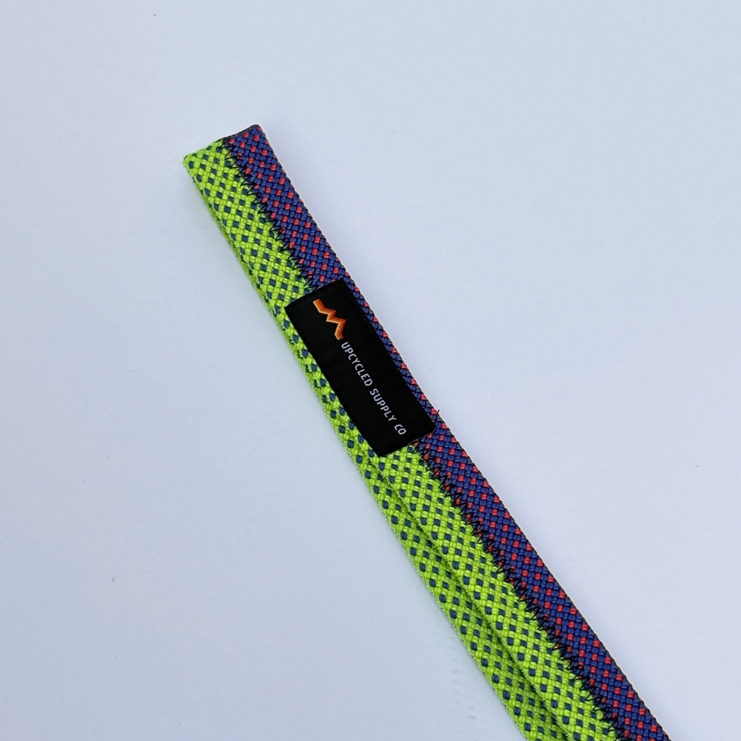 Multicolored webbing strap with a brand label on a light gray background
