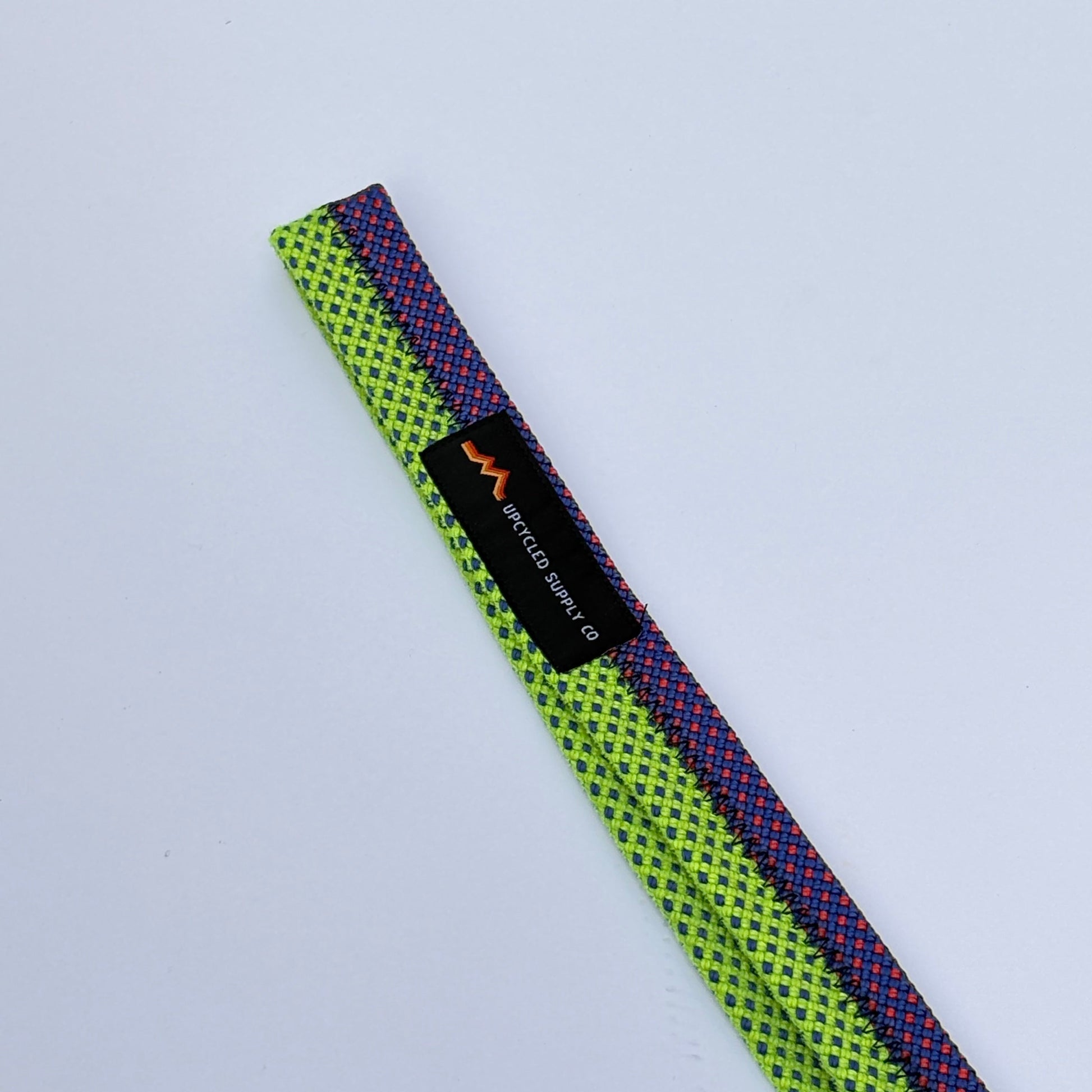Multicolored webbing strap with a brand label on a light gray background