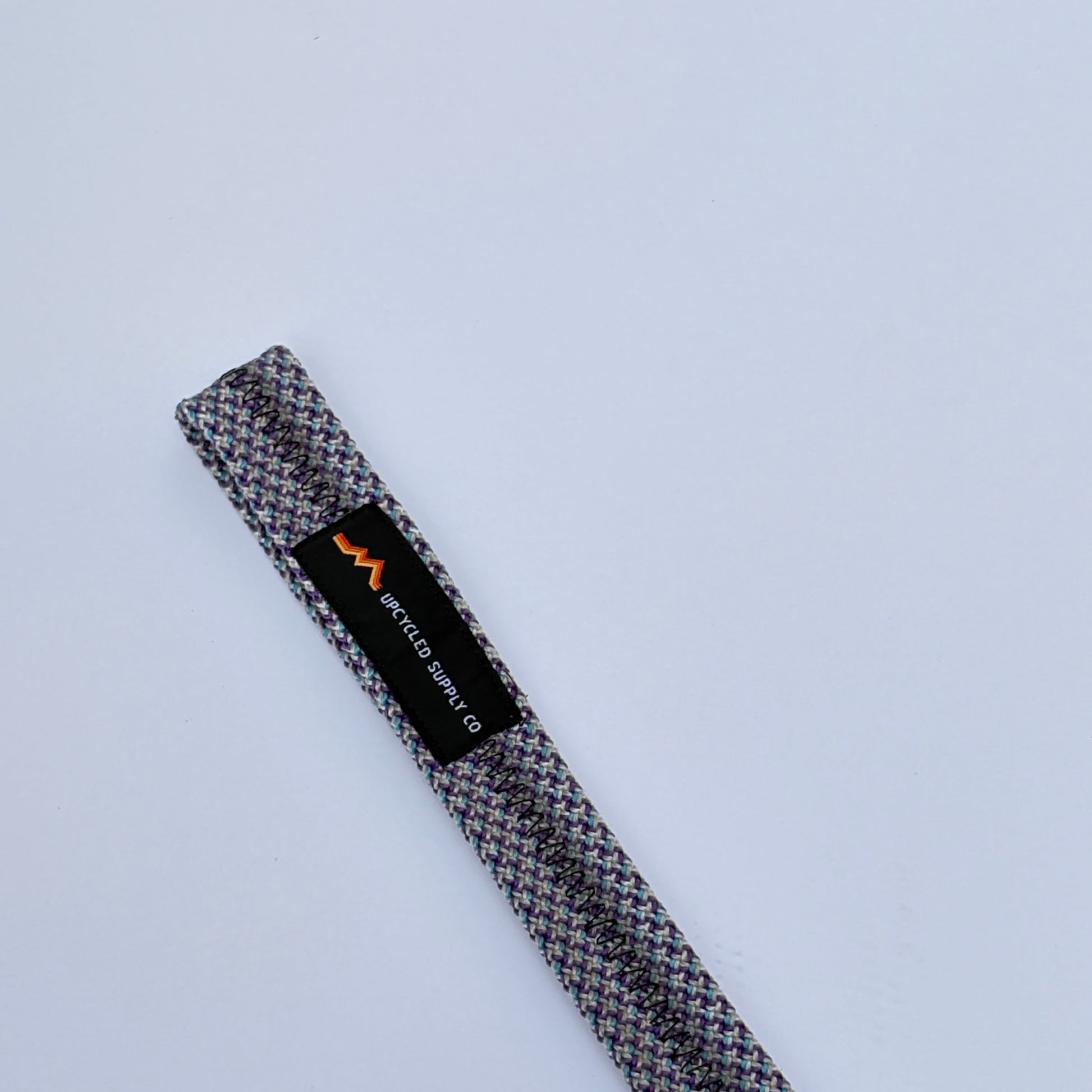 Textured belt with a brand label on a light gray background