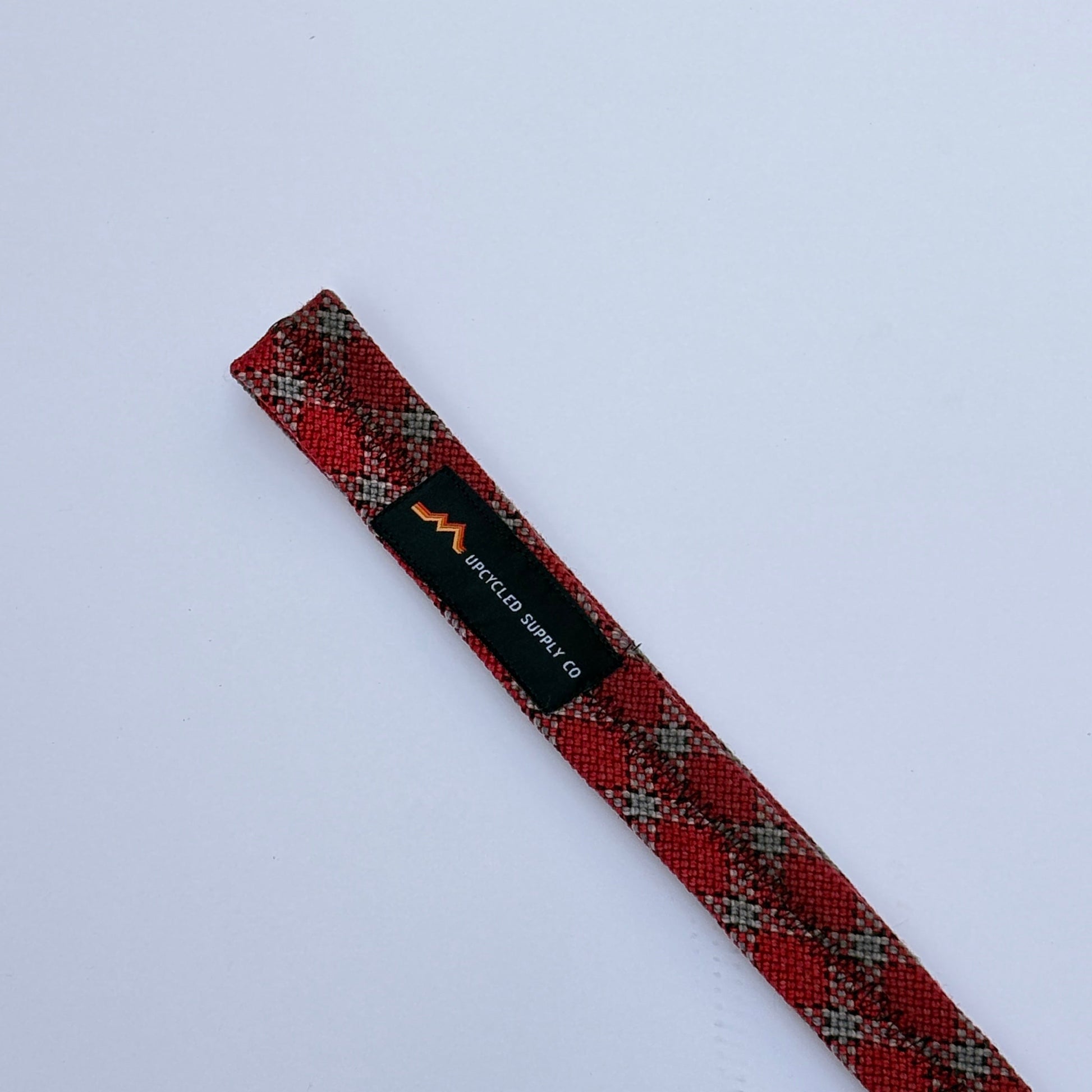 Red plaid tie with a brand label on a light gray background