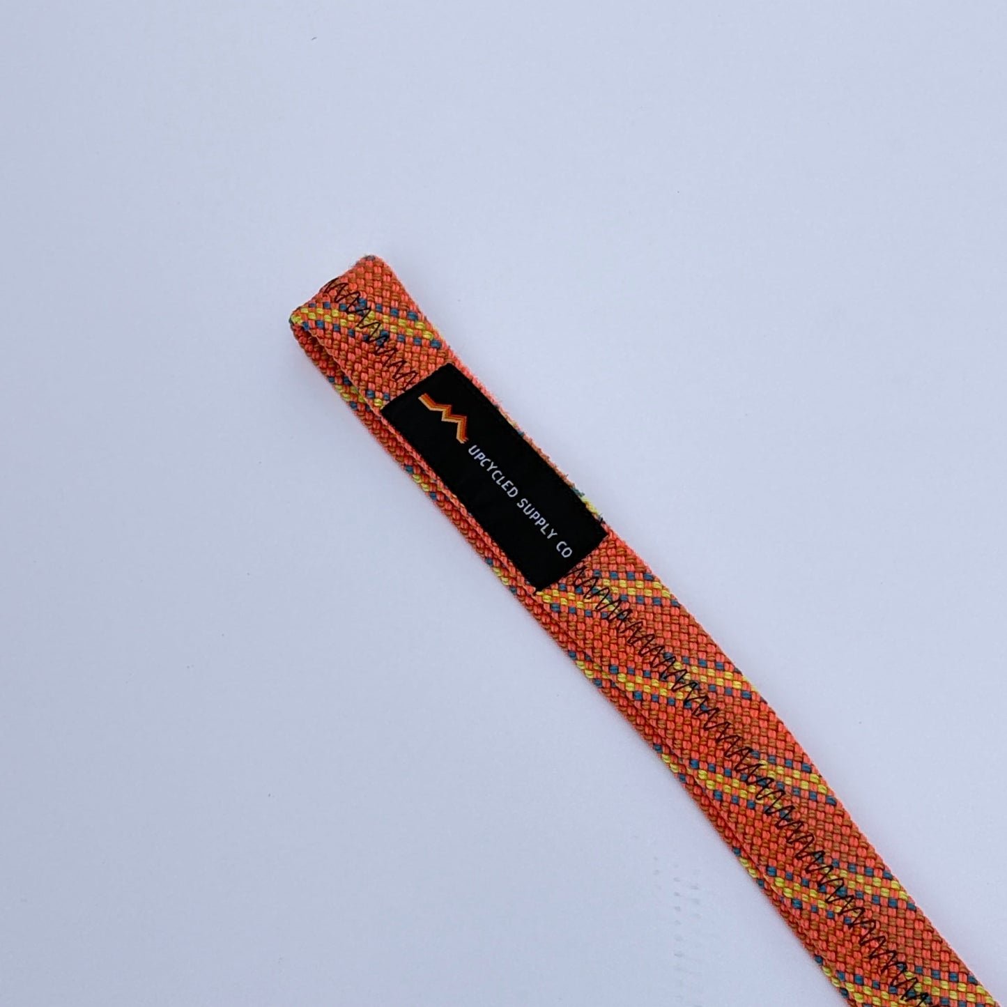 Textured orange and black strap with a label on a light gray background