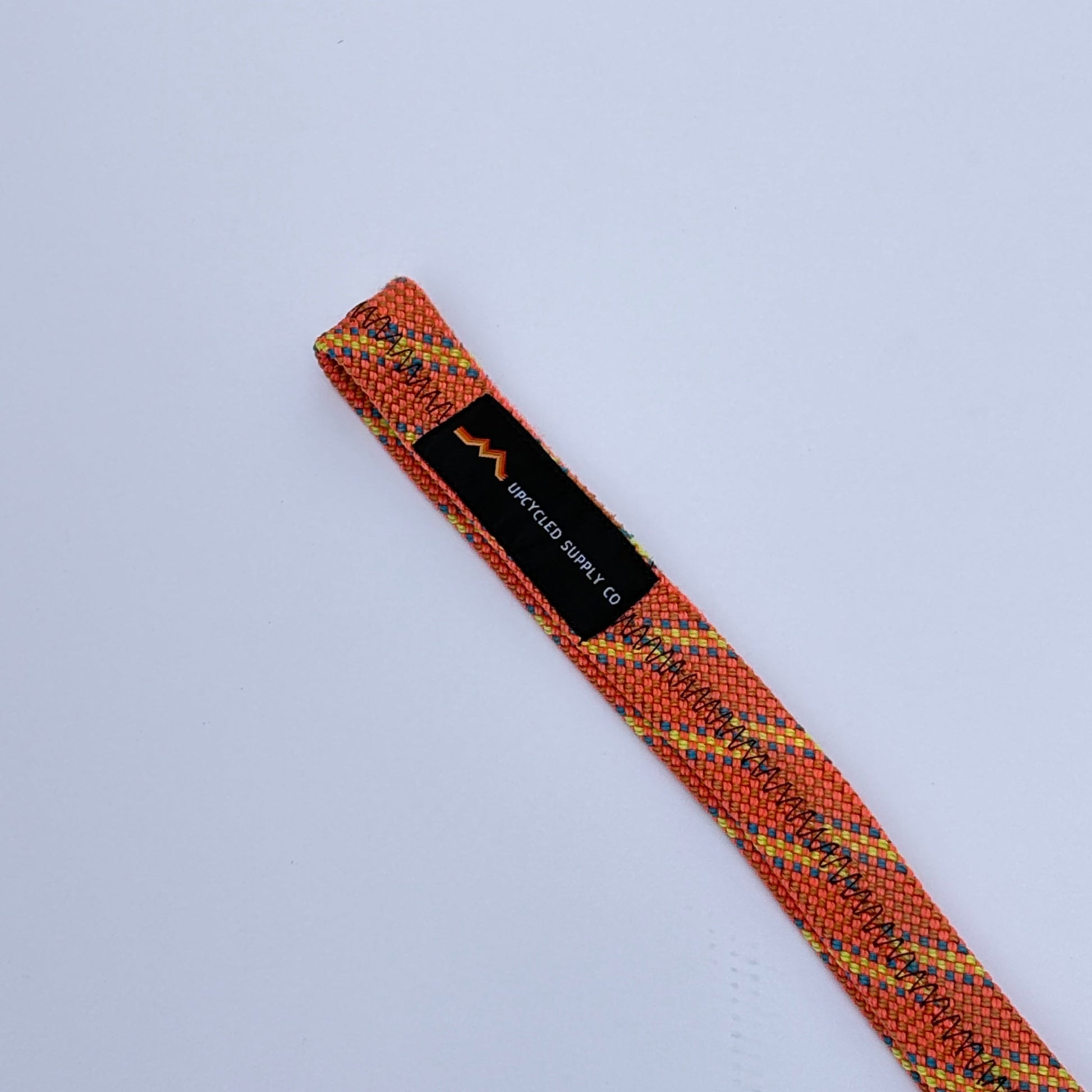 Textured orange and black strap with a label on a light gray background
