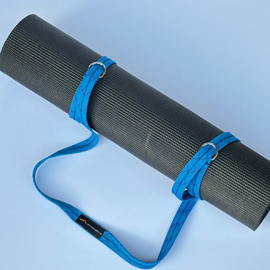 Black yoga mat with a blue carrying strap on a light blue background