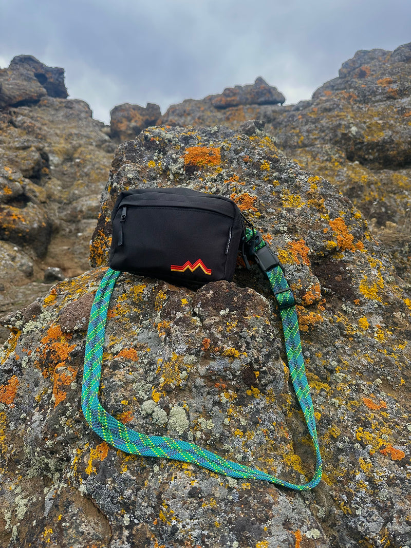 Black waist bag with a colorful strap on a rocky surface