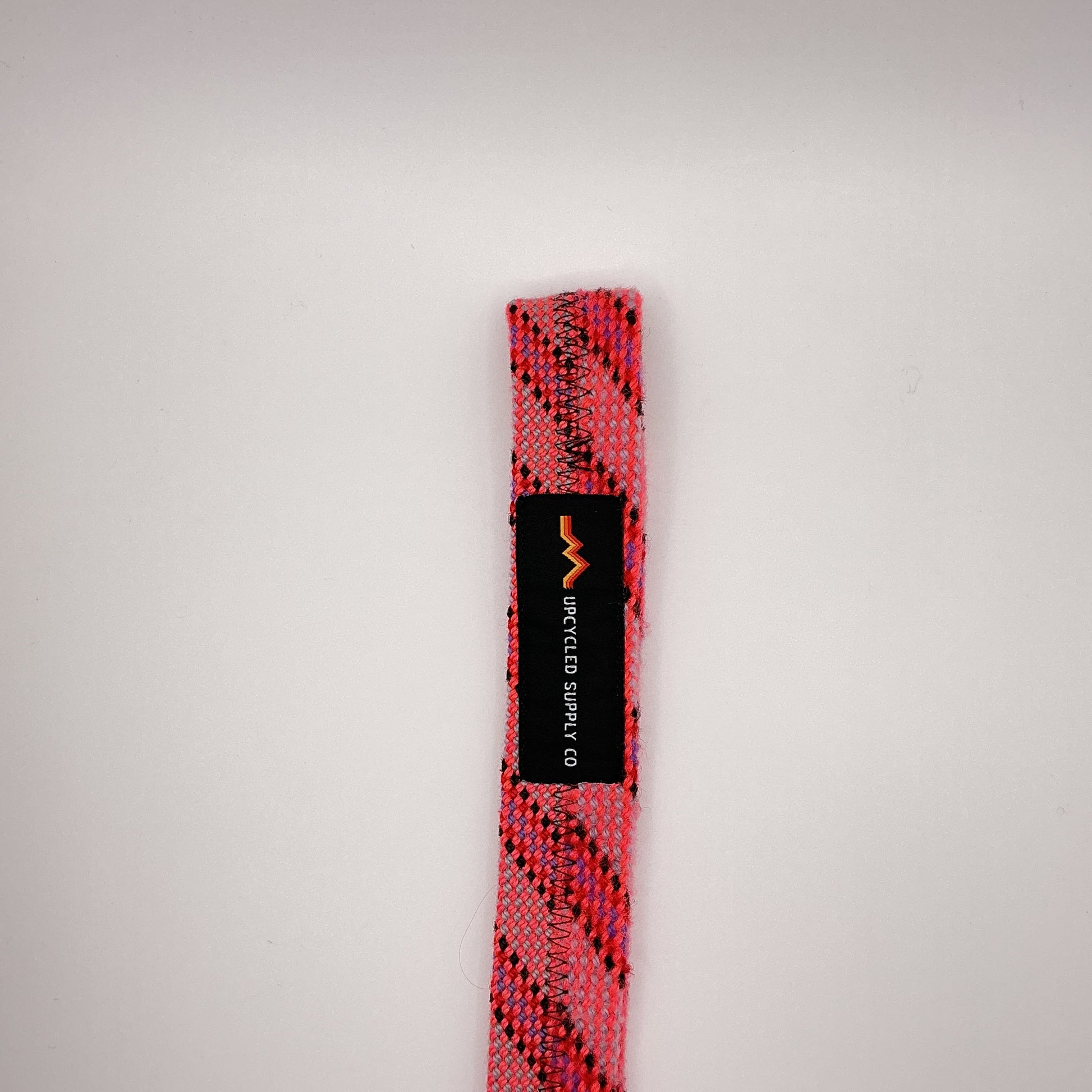 Pink and Black Yoga mat strap with a brand label on a light gray background