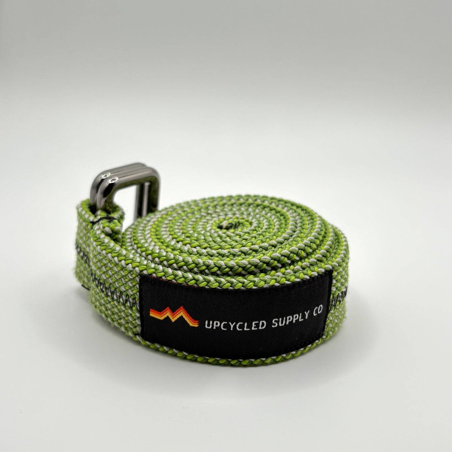 Green webbing strap with a brand label on a light gray background