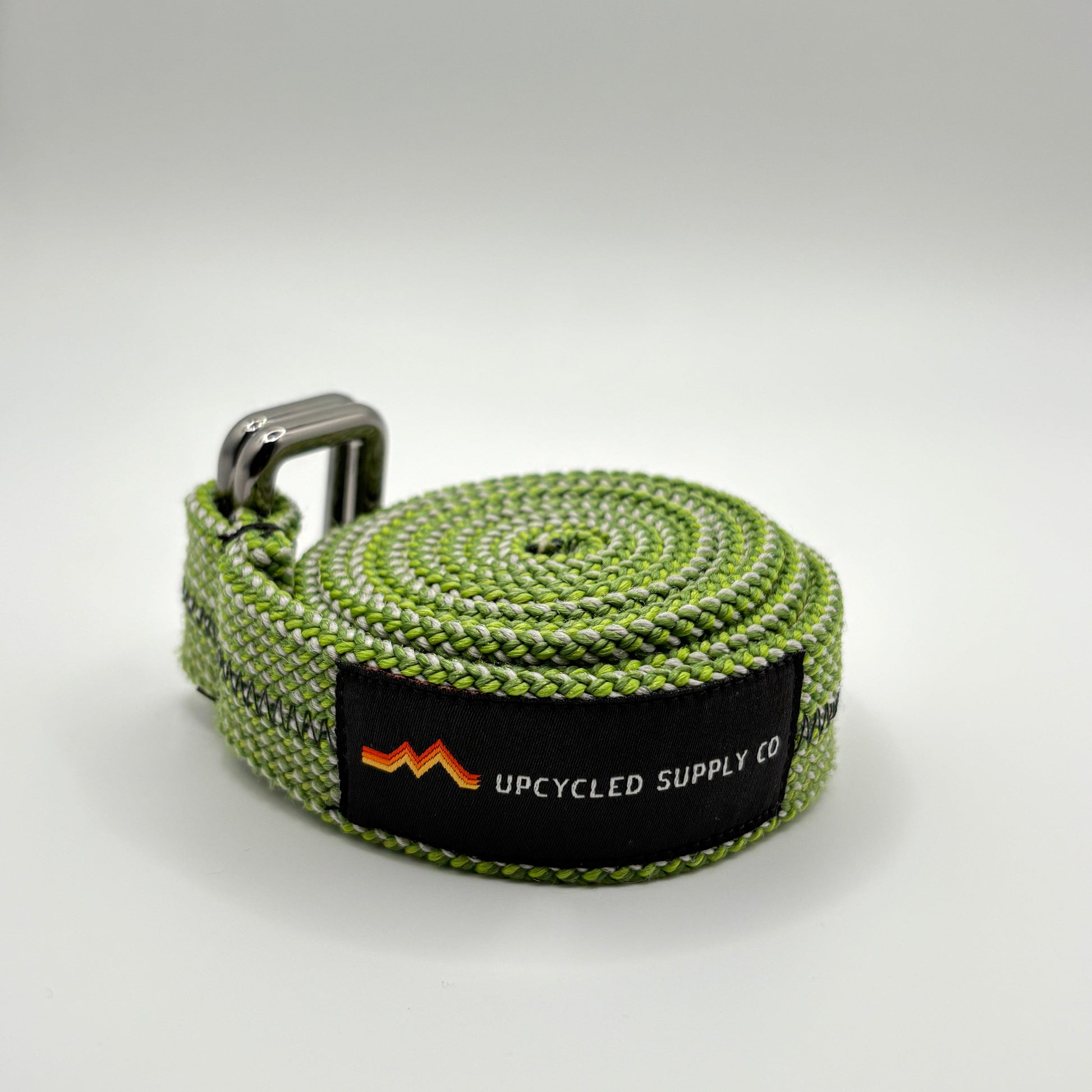 Green webbing strap with a brand label on a light gray background