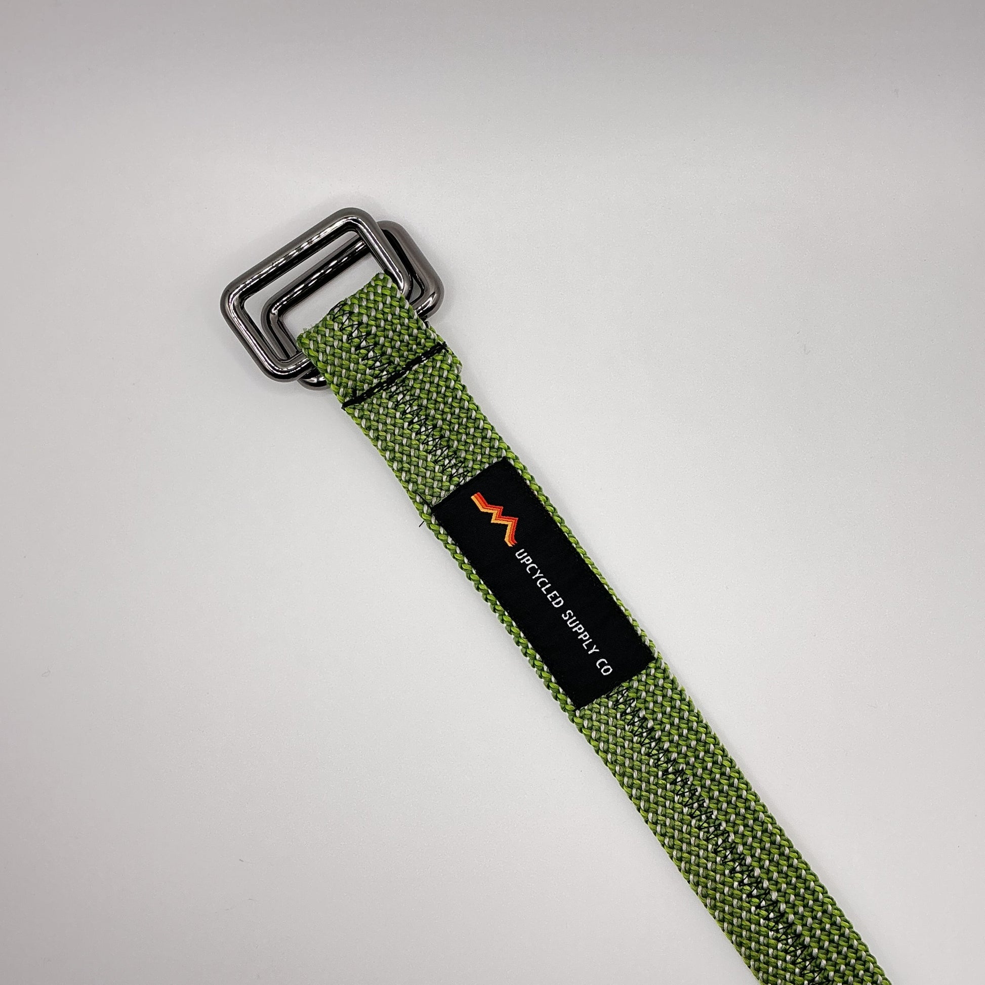 Green webbing strap with a buckle and visible brand logo on a light gray background