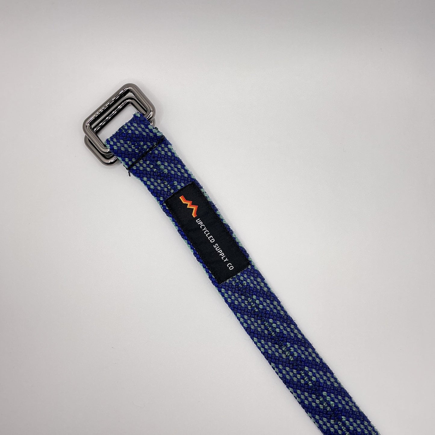 Blue webbing strap with a metal buckle on a light gray background