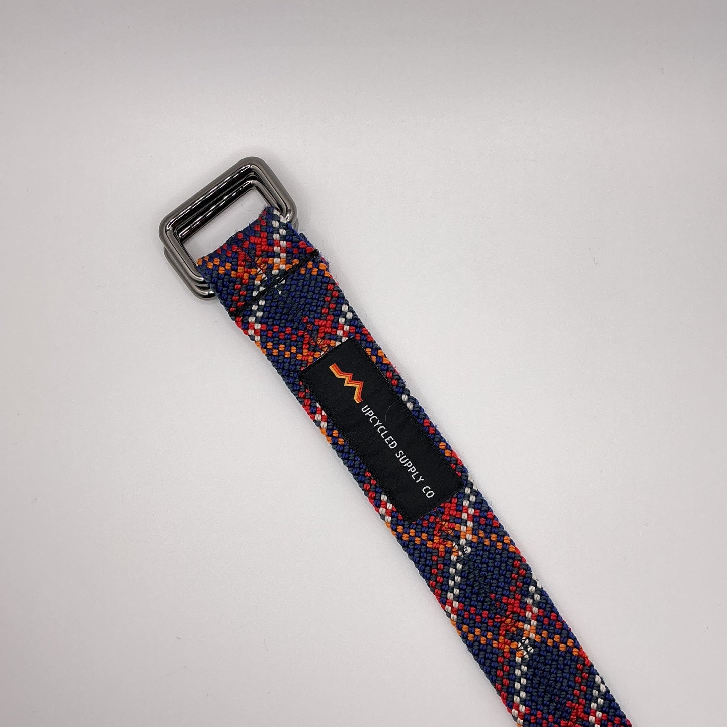 Multicolored woven belt with a silver buckle on a light gray background
