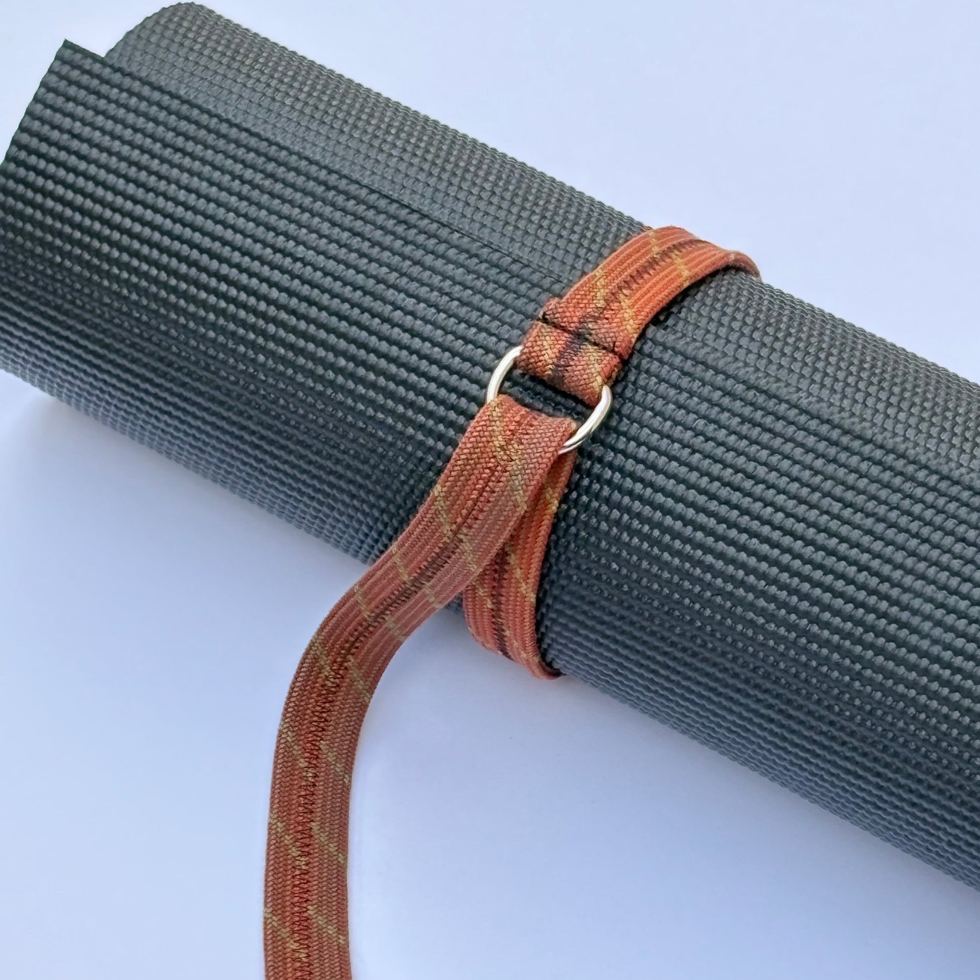 Yoga mat with a brown strap on a light blue background