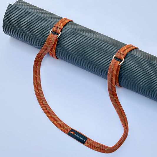 Yoga mat with a brown strap on a light gray background