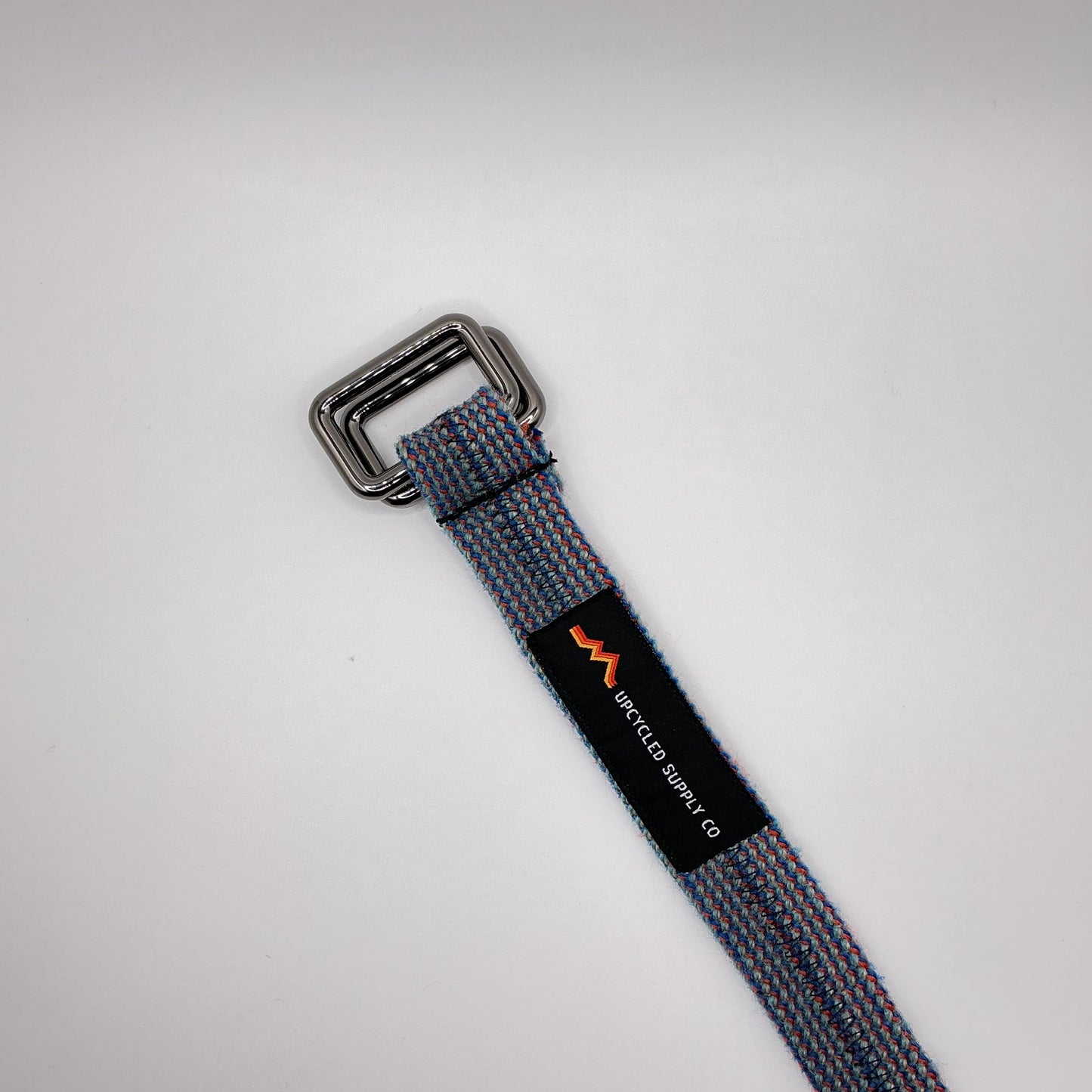 Gray webbing strap with a metal buckle on a light gray background
