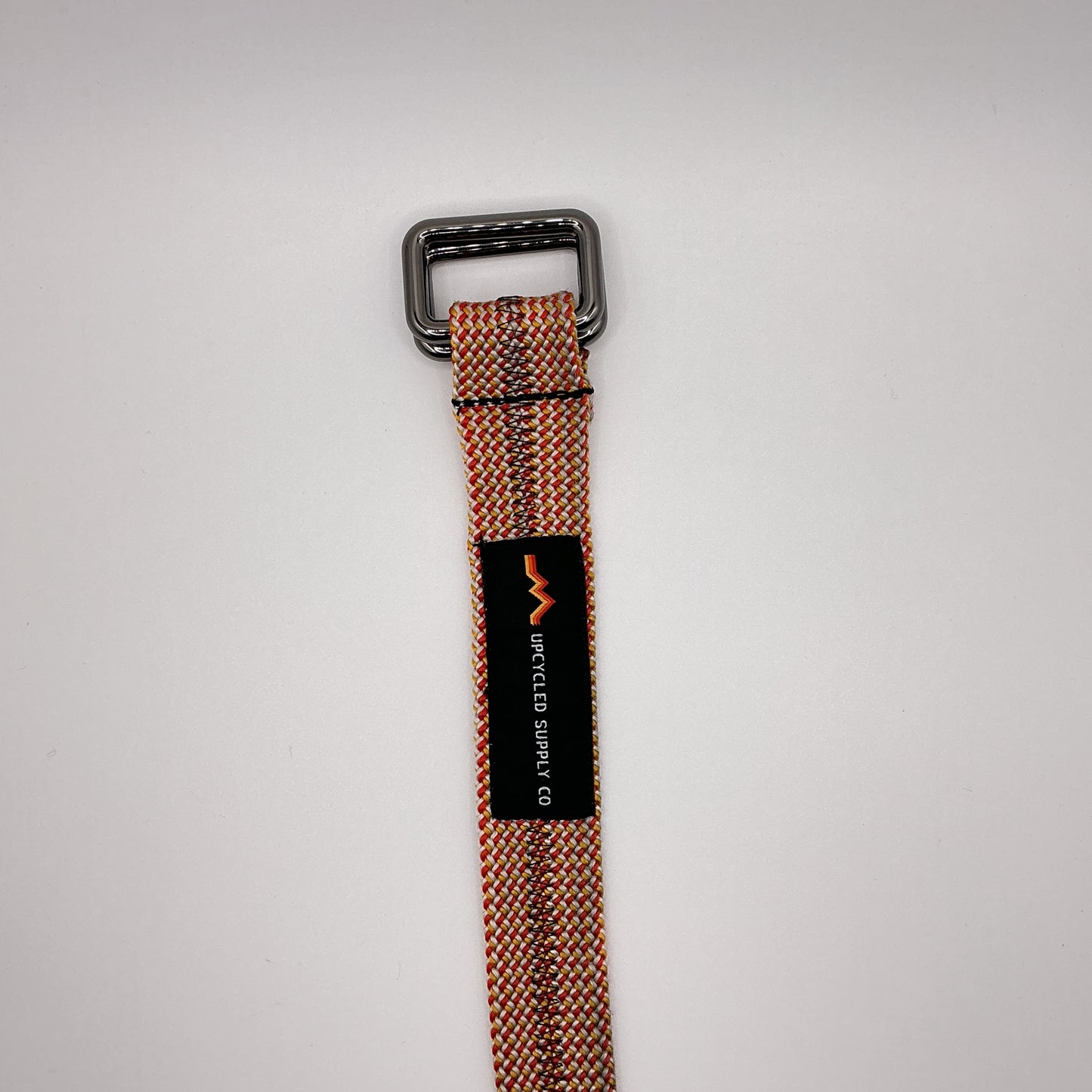Brown belt with a black buckle and label on a light gray background