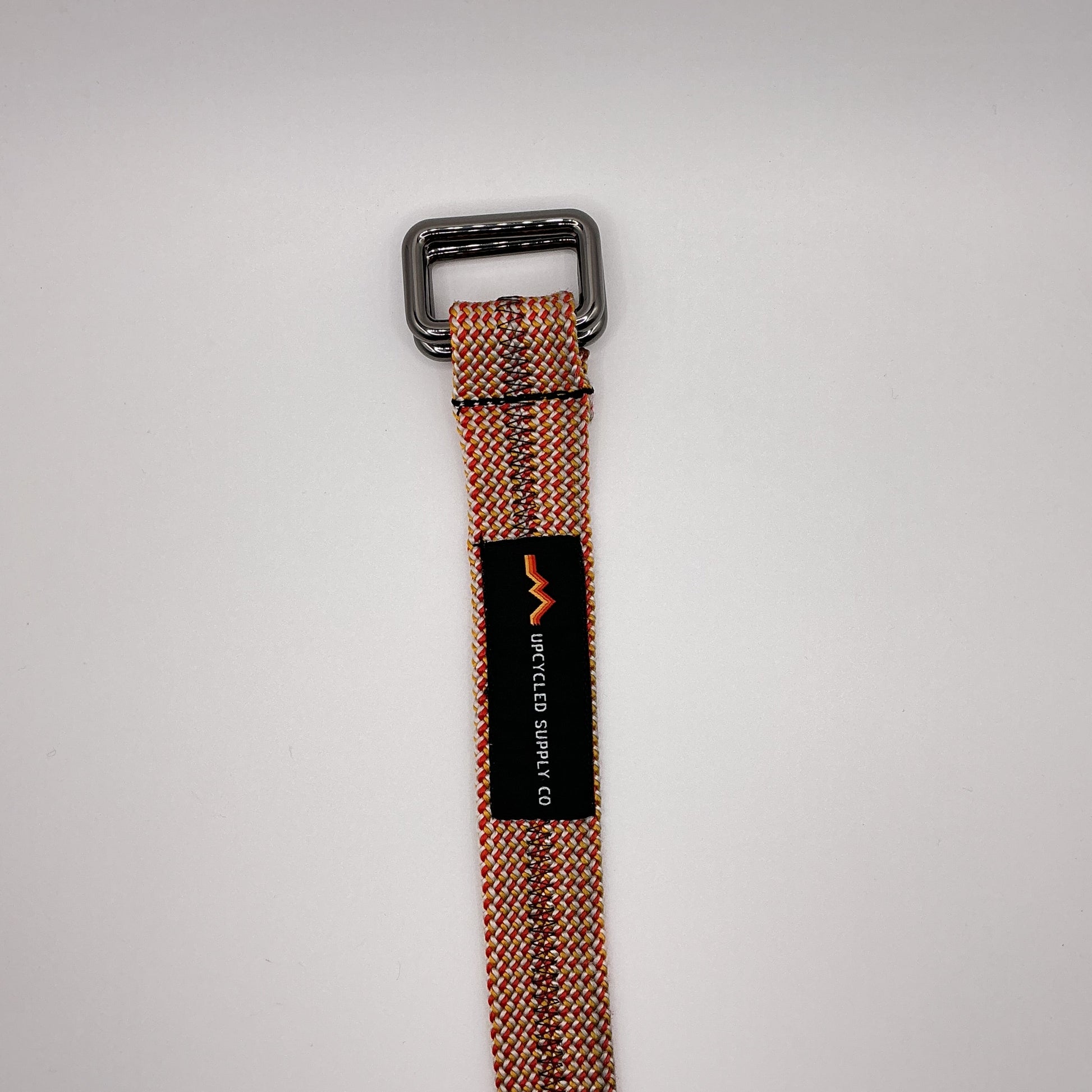 Brown belt with a black buckle and label on a light gray background