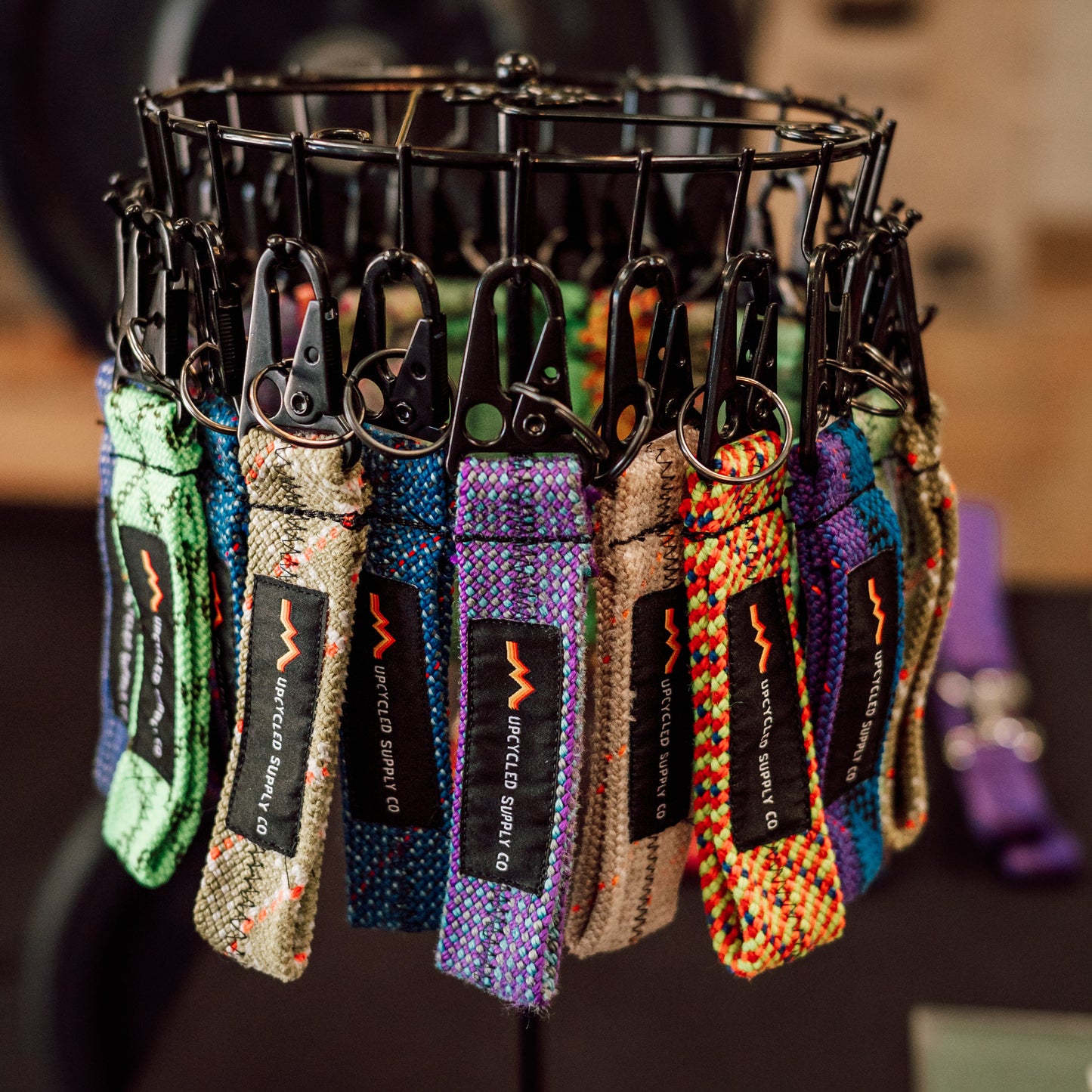 Collection of colorful keychains on a black stand with a blurred background