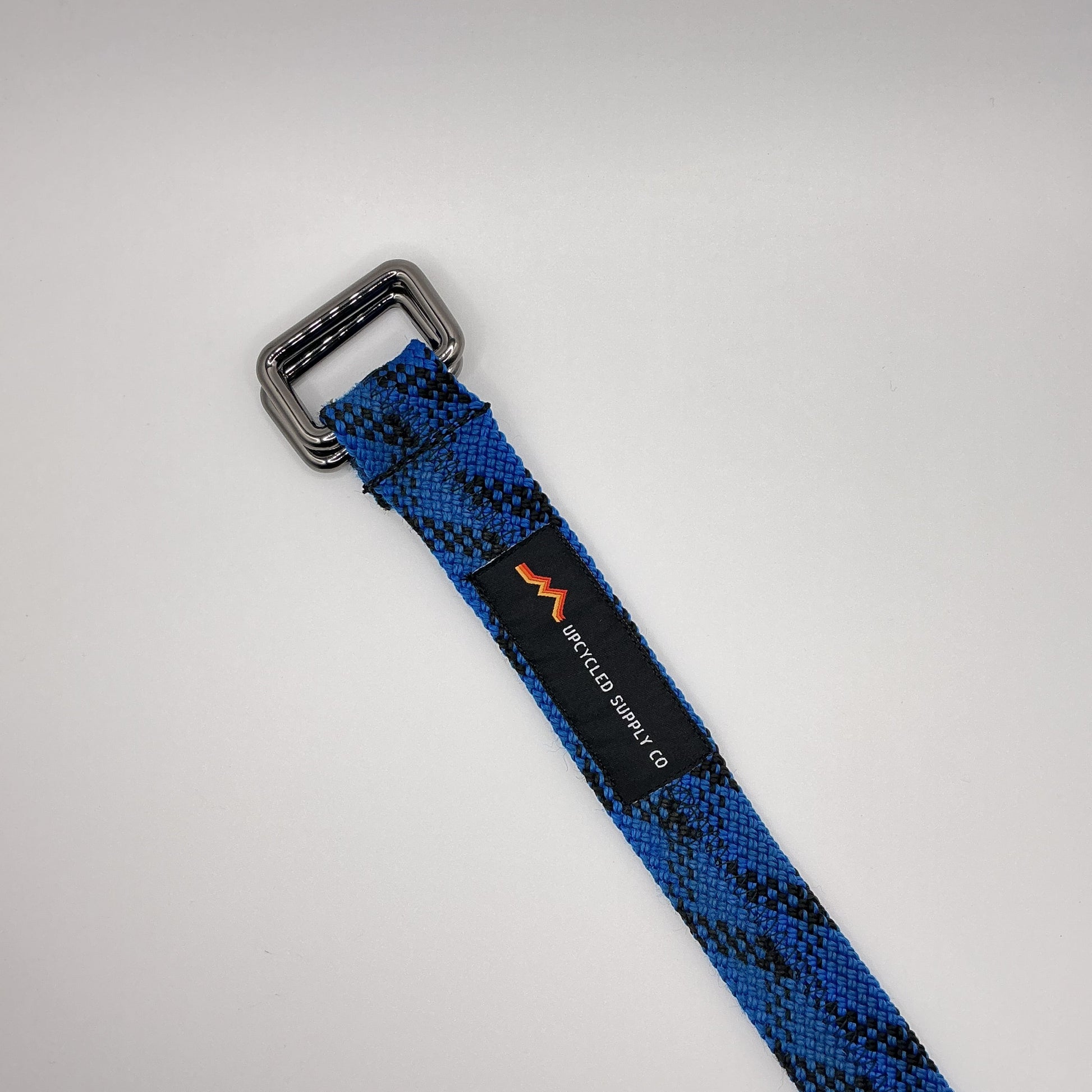 Blue and black patterned belt with a silver buckle on a light gray background