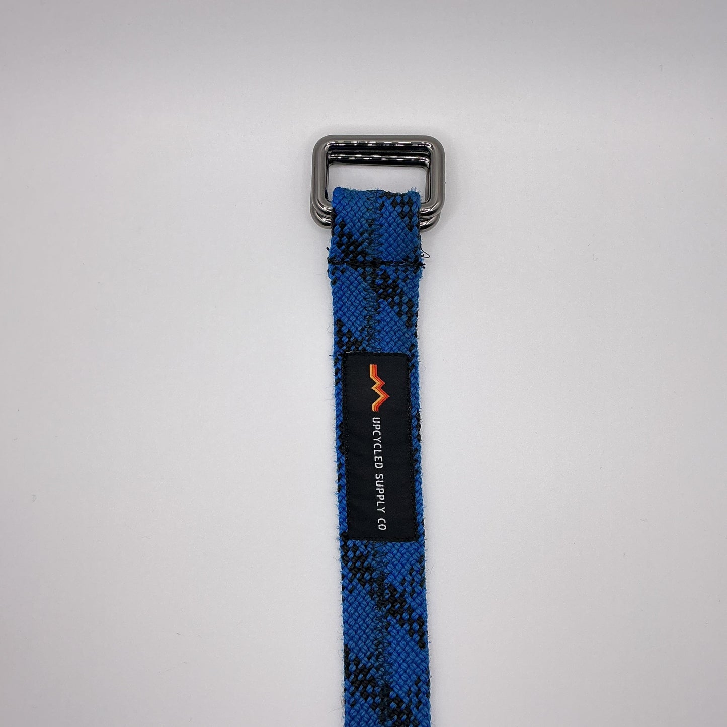 Blue and black checkered strap with a metal buckle on a light gray background